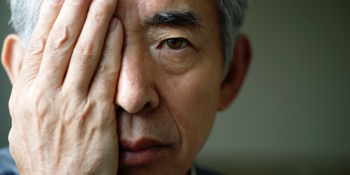 A man is covering his right eye with his hand